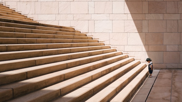 petit enfant au pied d'un immense escalier, comme un novice au pied d'une expertise à acquérir