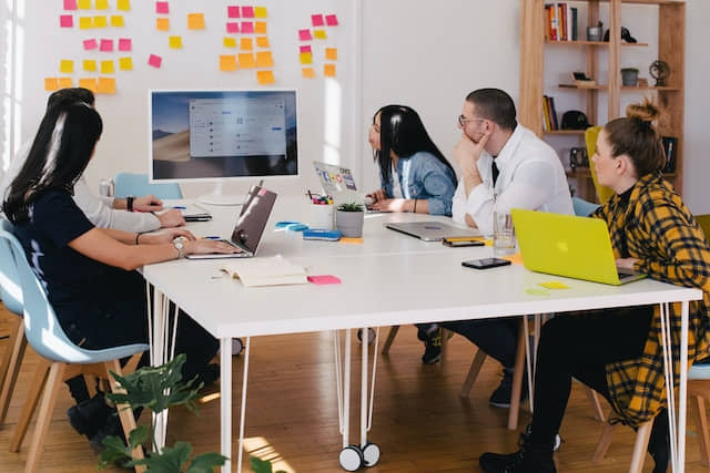 Une équipe à une table de travail, tournée vers des post it affichés.